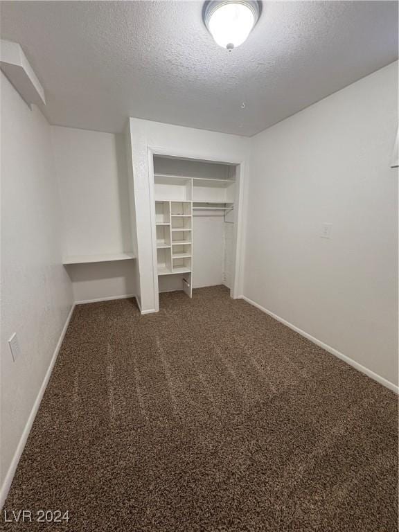 unfurnished bedroom featuring a closet, dark carpet, and a textured ceiling