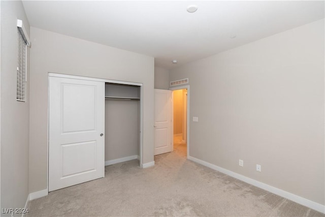 unfurnished bedroom featuring a closet and light colored carpet