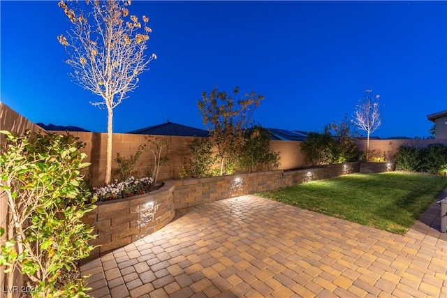 patio at night featuring a lawn