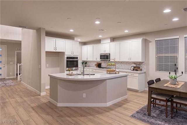 kitchen featuring stainless steel appliances, sink, a center island with sink, light hardwood / wood-style flooring, and white cabinetry