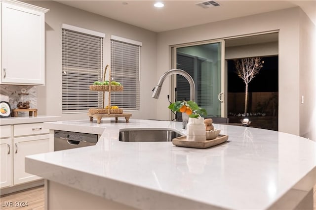 kitchen with white cabinets, a kitchen island with sink, dishwasher, and sink