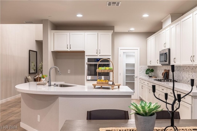 kitchen featuring backsplash, white cabinetry, sink, and appliances with stainless steel finishes