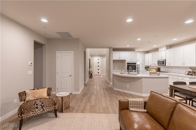 kitchen with white cabinets, stainless steel appliances, light hardwood / wood-style floors, and sink