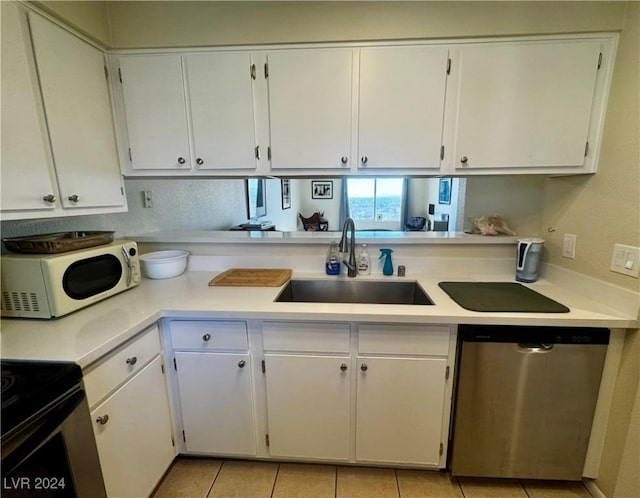 kitchen featuring stainless steel dishwasher, light tile patterned flooring, white cabinets, and sink