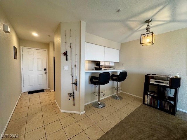 kitchen with a kitchen bar, kitchen peninsula, white cabinetry, and light tile patterned flooring