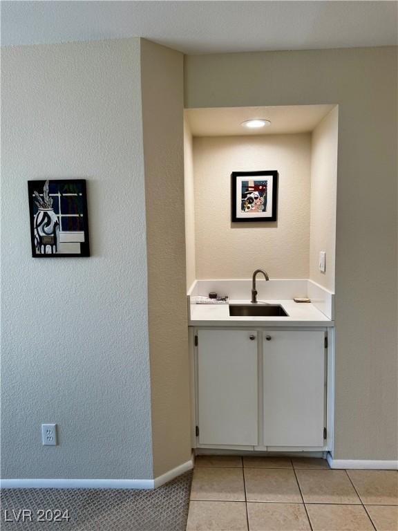 interior space with white cabinetry, sink, and light tile patterned floors