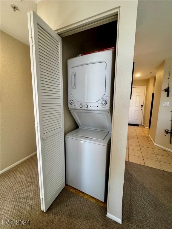 clothes washing area with carpet floors, baseboards, stacked washer / drying machine, and laundry area