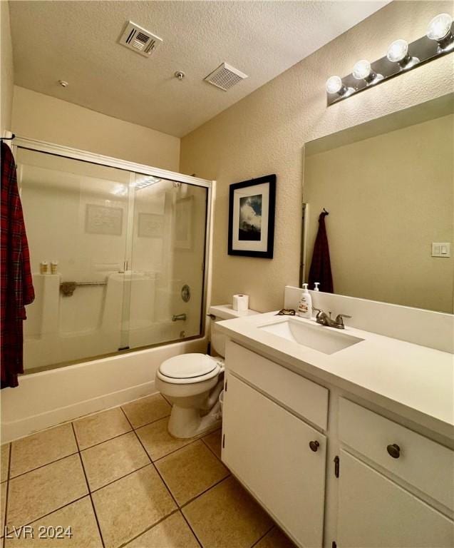 full bathroom featuring tile patterned floors, vanity, a textured ceiling, enclosed tub / shower combo, and toilet