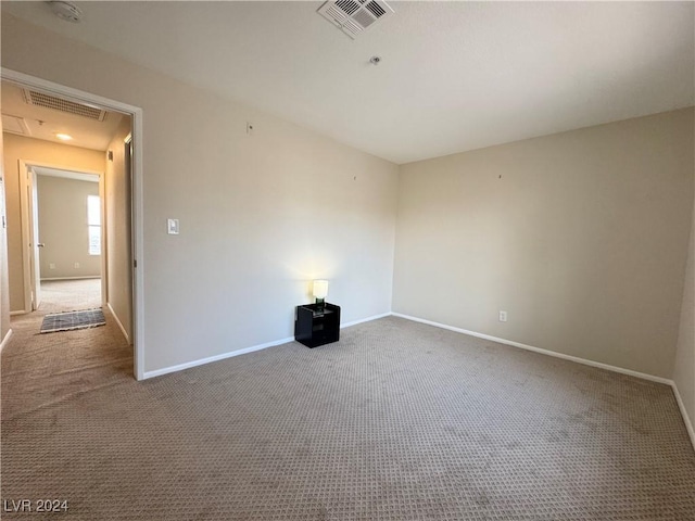carpeted empty room with baseboards, attic access, and visible vents