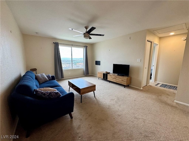 living room with carpet floors, a ceiling fan, baseboards, and attic access