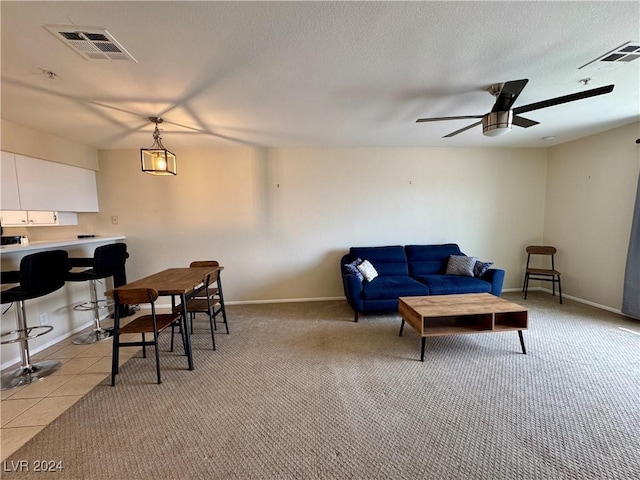 living area featuring visible vents, a ceiling fan, baseboards, and light colored carpet