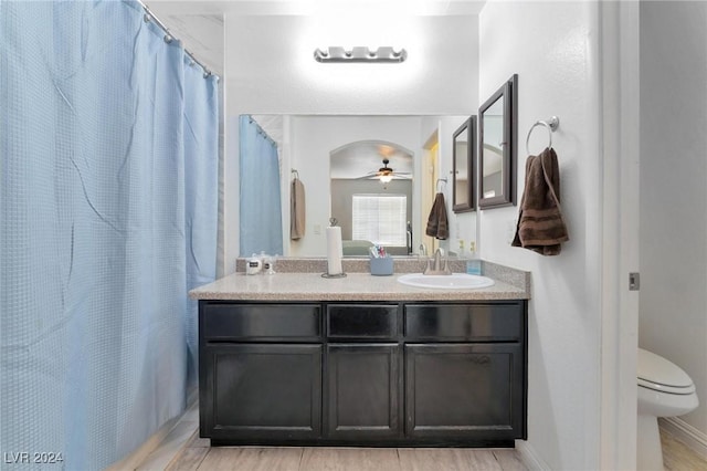 bathroom with a shower with shower curtain, ceiling fan, toilet, and vanity