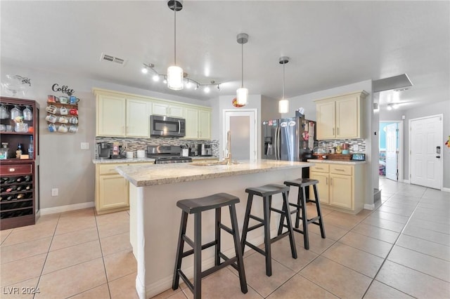 kitchen with tasteful backsplash, an island with sink, light tile patterned flooring, and appliances with stainless steel finishes