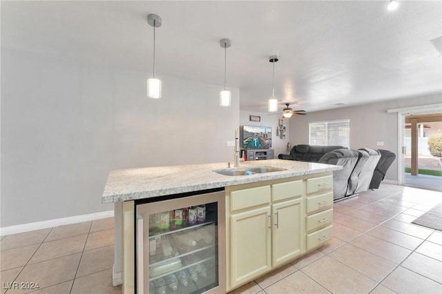 kitchen with pendant lighting, a kitchen island with sink, sink, wine cooler, and ceiling fan