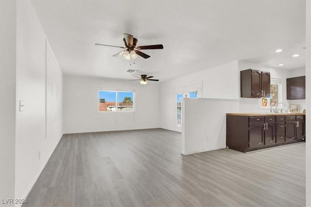 unfurnished living room with ceiling fan, light hardwood / wood-style floors, and sink