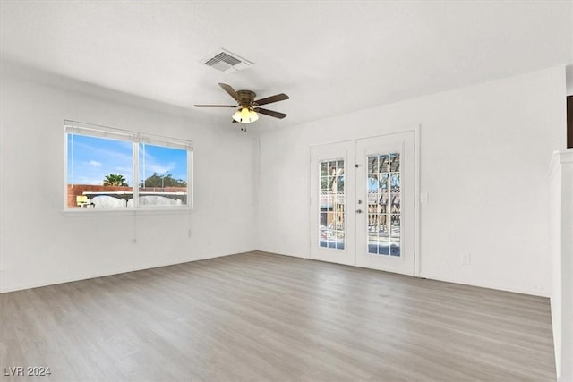 empty room featuring french doors, ceiling fan, a healthy amount of sunlight, and hardwood / wood-style floors