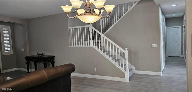 stairs with hardwood / wood-style floors and a notable chandelier