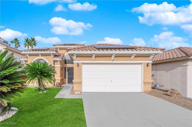 mediterranean / spanish-style house with solar panels, a garage, and a front lawn