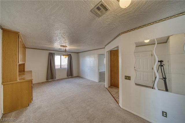 carpeted spare room featuring ornamental molding and a textured ceiling