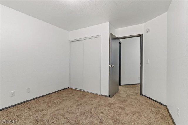 unfurnished bedroom featuring light carpet and a closet