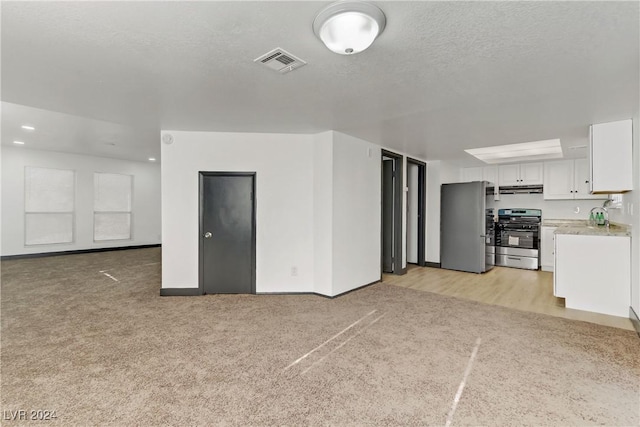 unfurnished living room featuring a textured ceiling and light colored carpet