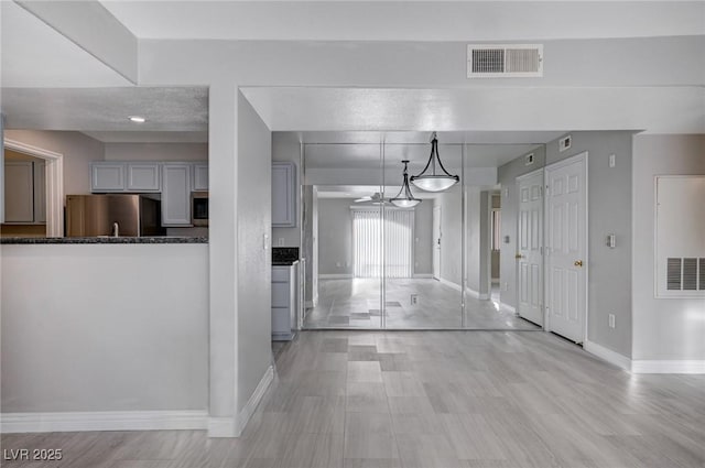 interior space with gray cabinetry, stainless steel appliances, and decorative light fixtures