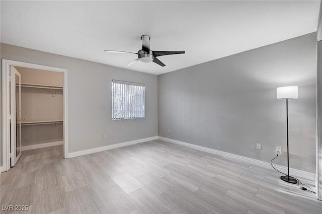 unfurnished bedroom featuring a walk in closet, a closet, and ceiling fan