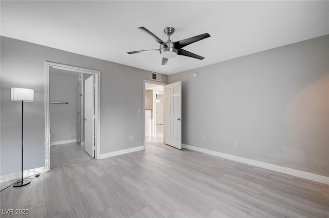 unfurnished bedroom featuring connected bathroom, ceiling fan, and a walk in closet