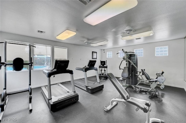 workout area with ceiling fan, a healthy amount of sunlight, and a textured ceiling