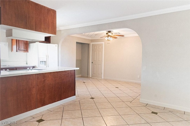 kitchen with ceiling fan, white refrigerator with ice dispenser, kitchen peninsula, crown molding, and light tile patterned floors