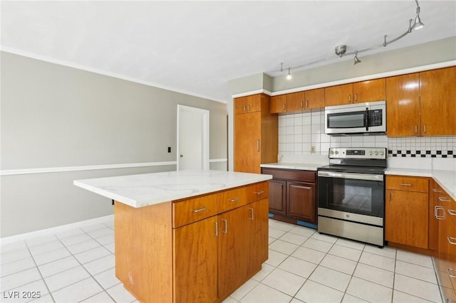 kitchen featuring tasteful backsplash, appliances with stainless steel finishes, a center island, and light tile patterned flooring