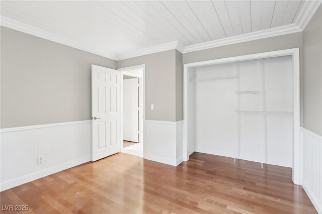 unfurnished bedroom featuring wood-type flooring, ornamental molding, and a closet