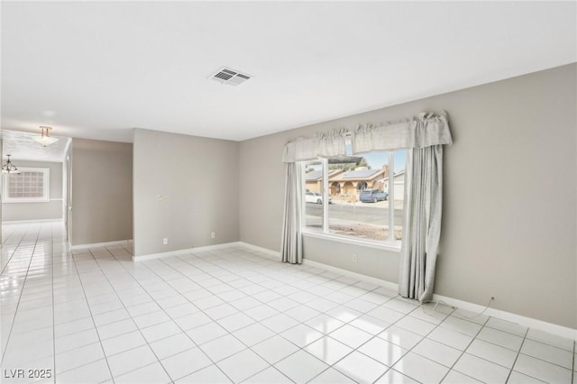 spare room with light tile patterned flooring and a chandelier