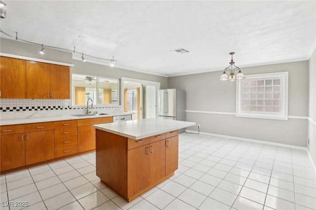 kitchen with sink, stainless steel fridge, backsplash, a center island, and light tile patterned flooring