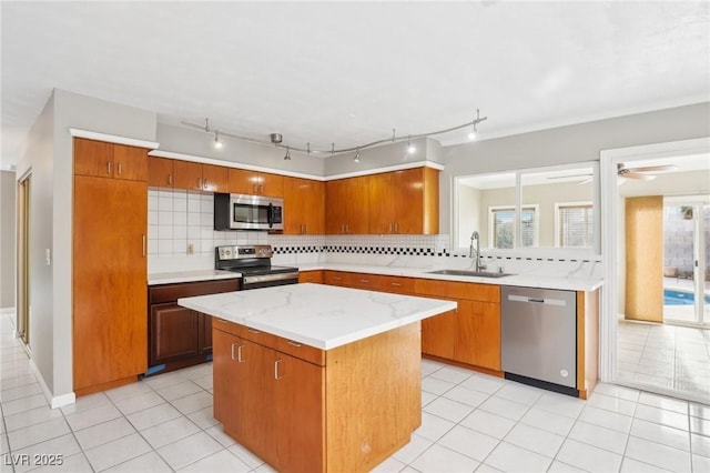 kitchen featuring sink, a center island, light tile patterned floors, appliances with stainless steel finishes, and decorative backsplash