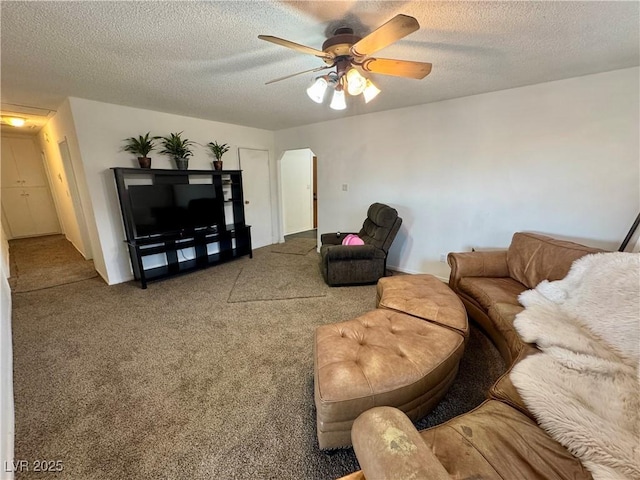 living area featuring arched walkways, carpet flooring, ceiling fan, and a textured ceiling