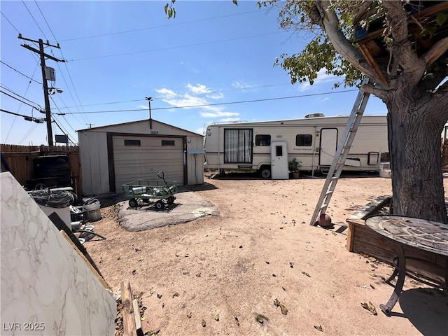 view of yard with a storage shed, a detached garage, fence, and an outdoor structure