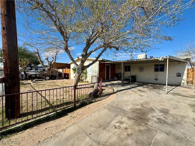 view of front of property with a patio area, fence, and stucco siding