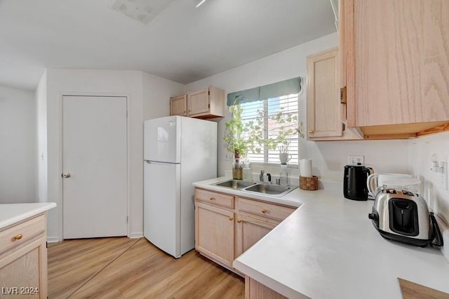 kitchen with sink, light brown cabinetry, light wood-type flooring, and white refrigerator