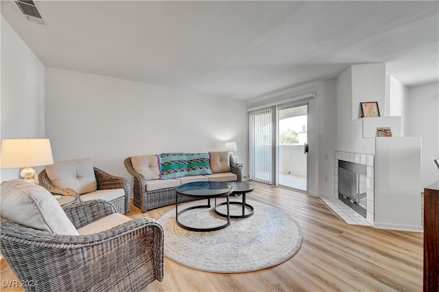 living room featuring light hardwood / wood-style floors and a tiled fireplace