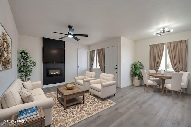 living room featuring hardwood / wood-style floors, ceiling fan, and a fireplace