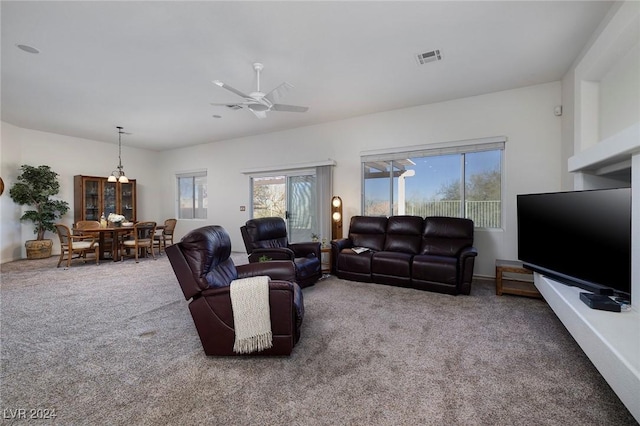 carpeted living room with ceiling fan with notable chandelier