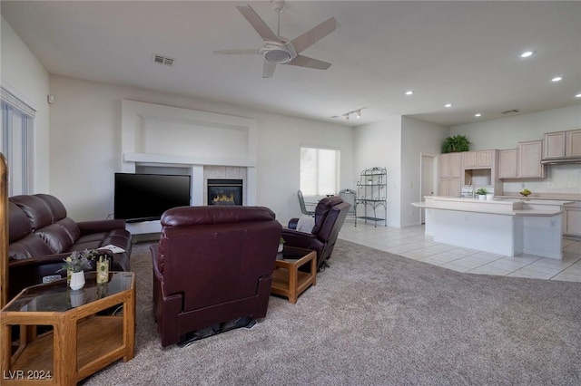 carpeted living room featuring a tile fireplace, ceiling fan, and rail lighting