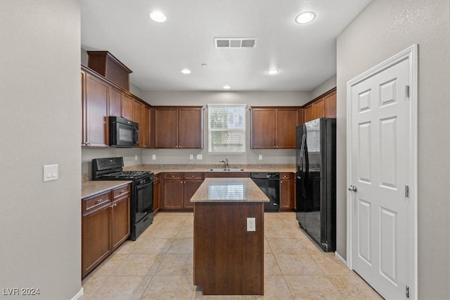 kitchen with sink, a kitchen island, light stone counters, light tile patterned flooring, and black appliances