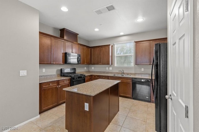 kitchen with a center island, black appliances, sink, light tile patterned flooring, and light stone counters