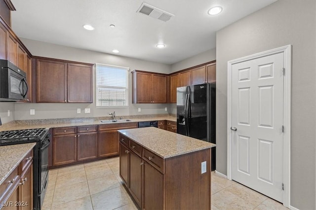 kitchen with light stone countertops, sink, light tile patterned floors, a kitchen island, and black appliances