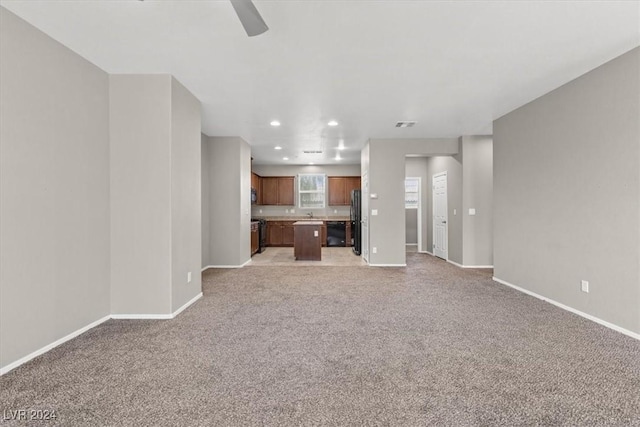 unfurnished living room with light carpet, sink, and ceiling fan