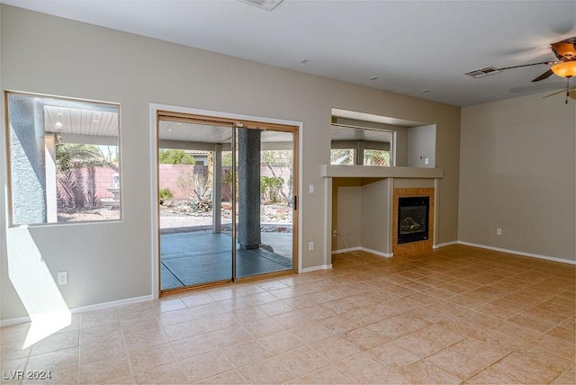 unfurnished living room with visible vents, a ceiling fan, baseboards, and a tile fireplace