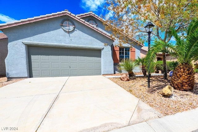 view of front of house with a tiled roof, an attached garage, driveway, and stucco siding