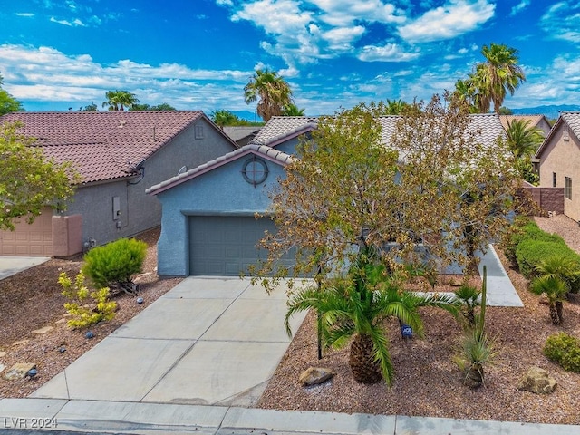 view of front of property featuring a tile roof, stucco siding, an attached garage, and concrete driveway